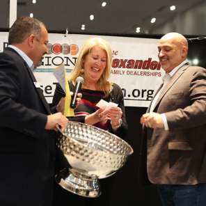 A woman drawing an organization name out of a silver bowl to receive a special award