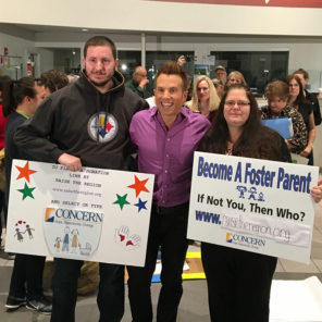 3 adults posing for a photo at the Raise the Region event holding signs in support of becoming a foster parent
