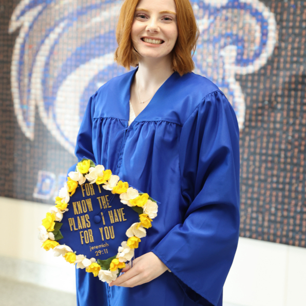 College student, Hannah, smiling while wearing her blue graduation gown