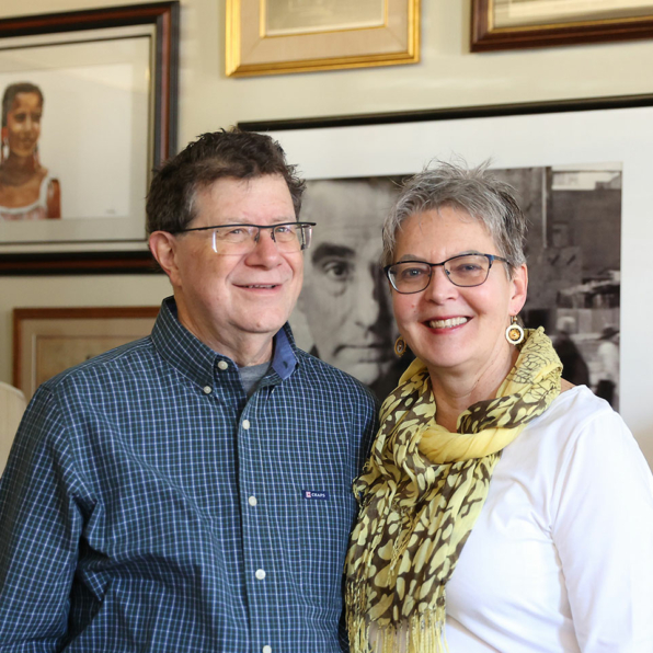 Steven and Teri smiling while standing in front of their private home art collection