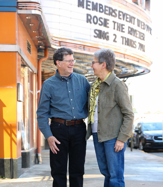 Steven and Teri casually laughing while walking past the community theatre