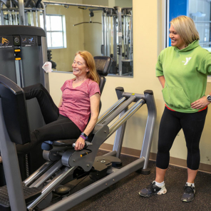 A female trainer watching another woman exercise on a weighted machine