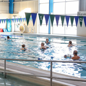 A couple of dozen class participants working out in a large indoorpool