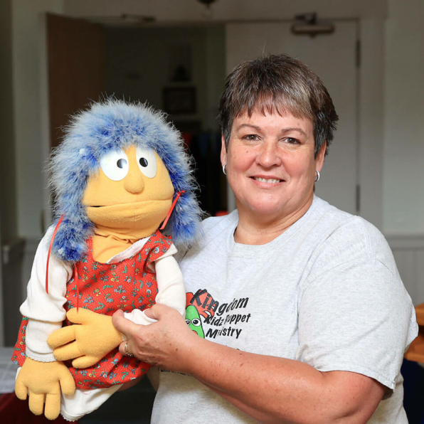 A puppeteer with Kingdom Kidz holding a blue-haired puppet